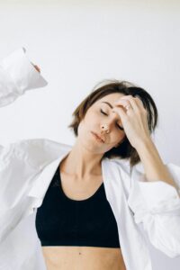 Young woman in a relaxed pose wearing a white shirt and black top in a serene indoor setting.